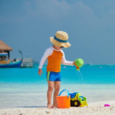 Üç yaşında bir çocuk sahilde oynuyor.