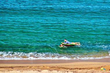 Çocuk ve annesi şişme kayan nokta ile sahilde