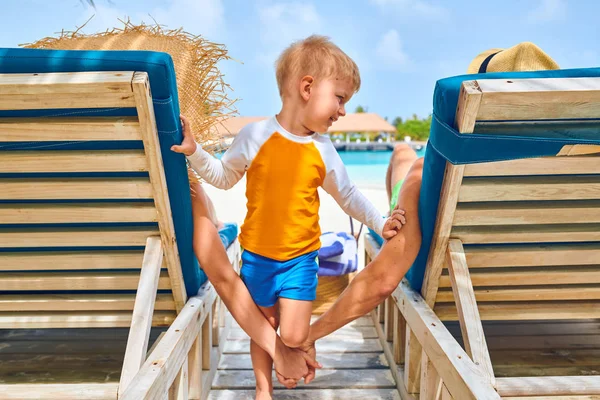 Familie op strand op houten ligstoelen bed — Stockfoto