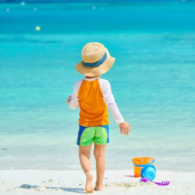 Üç yaşında bir çocuk sahilde oynuyor.