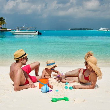 Üç yaşındaki bir çocukla plajda bir aile.