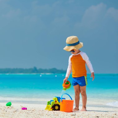 Üç yaşında bir çocuk sahilde oynuyor.