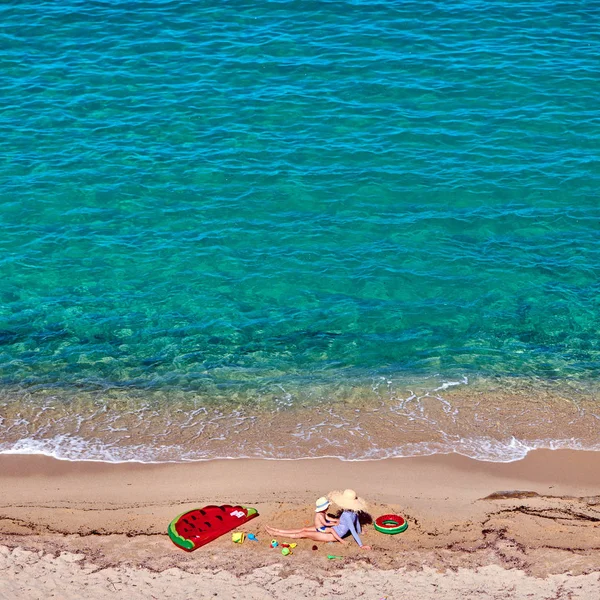 Ragazzo e sua madre sulla spiaggia con galleggiante gonfiabile — Foto Stock