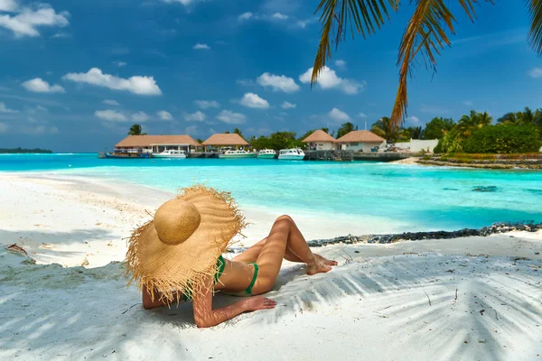 Woman sitting on beach under palm tree — Stock Photo, Image