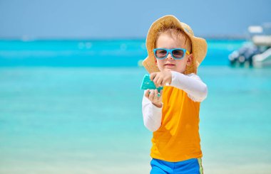 Üç yaşında bir çocuk sahilde oynuyor.