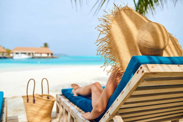 Vrouw aan het strand op houten ligstoelen bed — Stockfoto