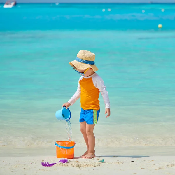 Üç yaşında bir çocuk sahilde oynuyor.