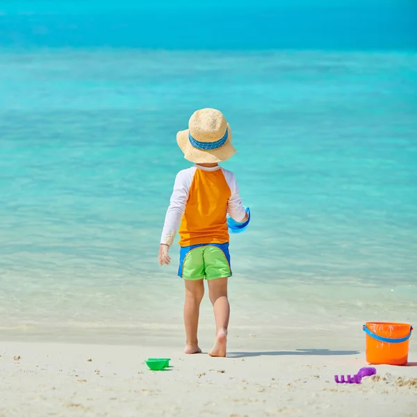 Üç yaşında bir çocuk sahilde oynuyor.