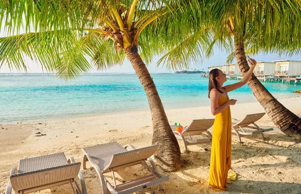 Mujer en vestido tomando selfie en la playa tropical — Foto de Stock