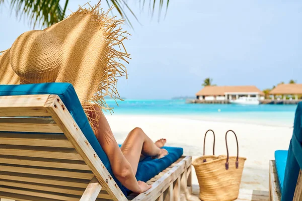 Vrouw aan het strand op houten ligstoelen bed — Stockfoto