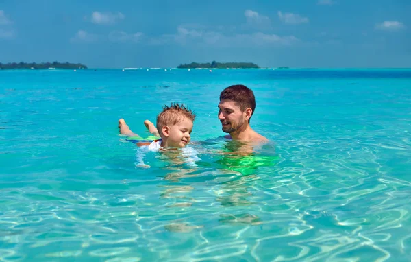 Toddler boy learns to swim with father