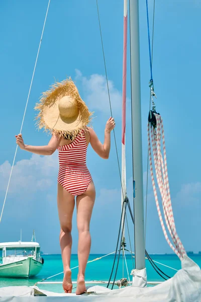 Woman in striped swimsuit standing on boat — Stock Photo, Image