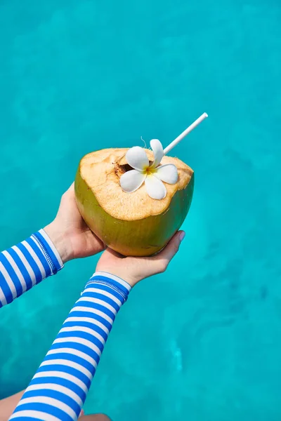 Coconut in hands over against turquoise sea — Stock Photo, Image