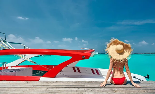 Mulher de biquíni sentada no molhe com barco — Fotografia de Stock