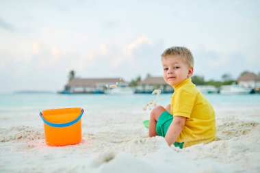 Üç yaşında bir çocuk sahilde oynuyor.