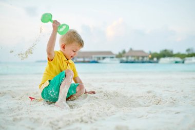 Üç yaşında bir çocuk sahilde oynuyor.