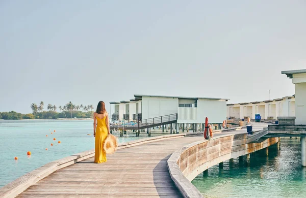 Tropik sahil kaldırımında yürüyen elbiseli bir kadın. — Stok fotoğraf