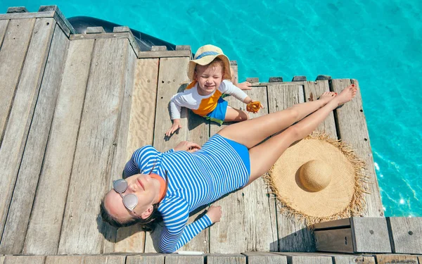 Toddler pojke med mor sitter på träbryggan — Stockfoto