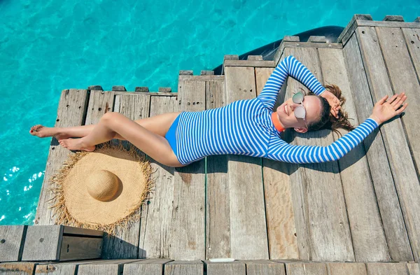 Woman in rash guard on wooden jetty