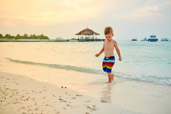 Drie-jarige peuter jongen op het strand bij zonsondergang — Stockfoto