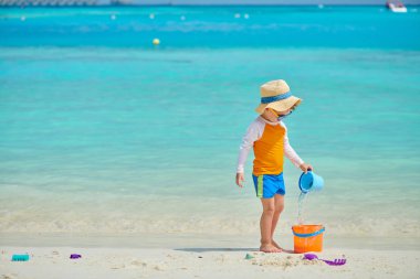 Üç yaşındaki yürümeye başlayan çocuk sahilde plaj oyuncakları ile oynarken. Maldivler aile tatil yaz.