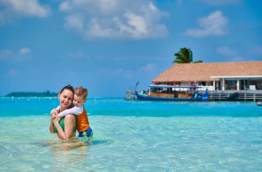 Üç yaşındaki yürümeye başlayan çocuk sığ suda eğlenmek annesi ile sahilde. Maldivler aile tatil yaz.