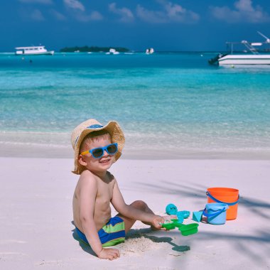 Üç yaşındaki yürümeye başlayan çocuk sahilde plaj oyuncakları ile oynarken. Maldivler aile tatil yaz.