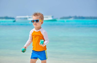 Üç yaşındaki yürümeye başlayan çocuk sahilde plaj oyuncakları ile oynarken. Maldivler aile tatil yaz.