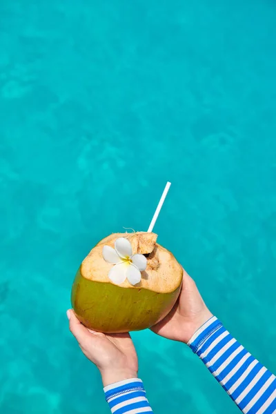 Coconut in hands over against turquoise sea — Stock Photo, Image