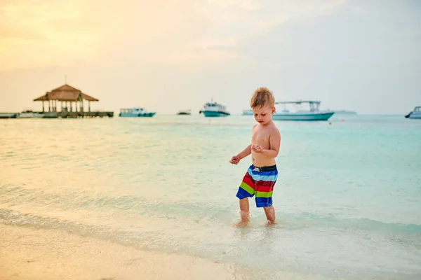 Drie-jarige peuter jongen op het strand bij zonsondergang — Stockfoto