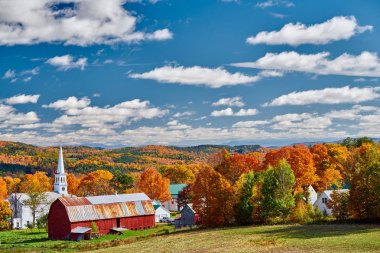 Sonbaharda kırmızı ahırı olan kilise ve çiftlik.