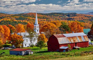 Sonbaharda kırmızı ahırı olan kilise ve çiftlik.