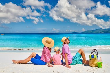 Güzel Anse Soleil plajında bir aile, üç yaşında bir çocuğu olan genç bir çift. Seyşeller 'de yaz tatili, Mahe..