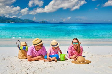 Güzel Anse Soleil plajında bir aile, üç yaşında bir çocuğu olan genç bir çift. Seyşeller 'de yaz tatili, Mahe..