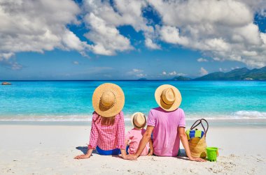 Güzel Anse Soleil plajında bir aile, üç yaşında bir çocuğu olan genç bir çift. Seyşeller 'de yaz tatili, Mahe..