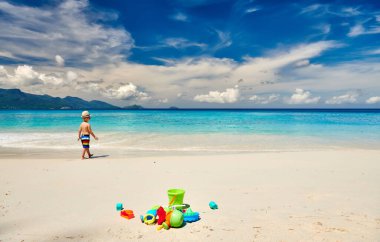 Üç yaşında bir çocuk sahilde plaj oyuncaklarıyla oynuyor. Seyşeller 'de yaz tatili, Mahe..
