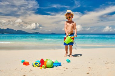 Üç yaşında bir çocuk sahilde plaj oyuncaklarıyla oynuyor. Seyşeller 'de yaz tatili, Mahe..