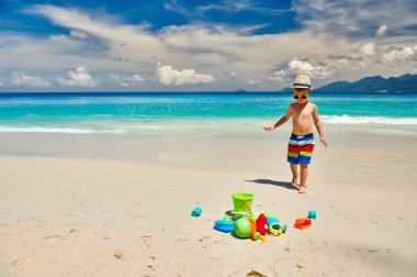 Üç yaşında bir çocuk sahilde plaj oyuncaklarıyla oynuyor. Seyşeller 'de yaz tatili, Mahe..