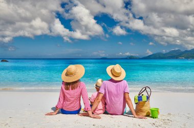 Güzel Anse Soleil plajında bir aile, üç yaşında bir çocuğu olan genç bir çift. Seyşeller 'de yaz tatili, Mahe..