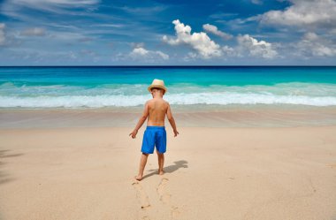 Sahilde yürüyen üç yaşında bir çocuk. Seyşeller 'de yaz tatili, Mahe..