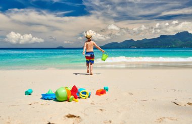 Üç yaşında bir çocuk sahilde plaj oyuncaklarıyla oynuyor. Seyşeller 'de yaz tatili, Mahe..