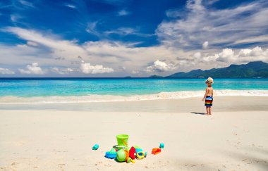 Üç yaşında bir çocuk sahilde plaj oyuncaklarıyla oynuyor. Seyşeller 'de yaz tatili, Mahe..