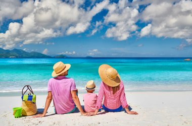 Güzel Anse Soleil plajında bir aile, üç yaşında bir çocuğu olan genç bir çift. Seyşeller 'de yaz tatili, Mahe..