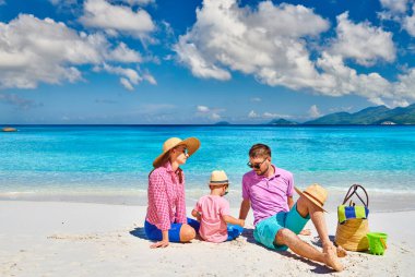 Güzel Anse Soleil plajında bir aile, üç yaşında bir çocuğu olan genç bir çift. Seyşeller 'de yaz tatili, Mahe..