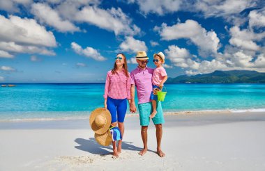 Güzel Anse Soleil plajında bir aile, üç yaşında bir çocuğu olan genç bir çift. Seyşeller 'de yaz tatili, Mahe..