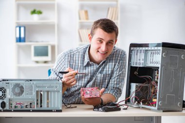 Genç teknisyen atölyede bilgisayar tamir ediyor.