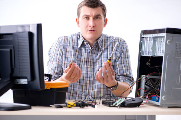 Young technician repairing computer in workshop