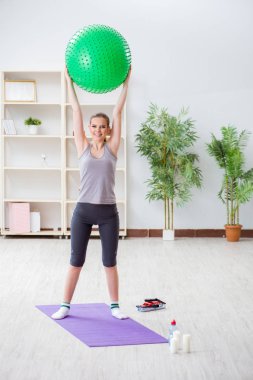 Spor salonunda denge topuyla egzersiz yapan genç bir kadın.