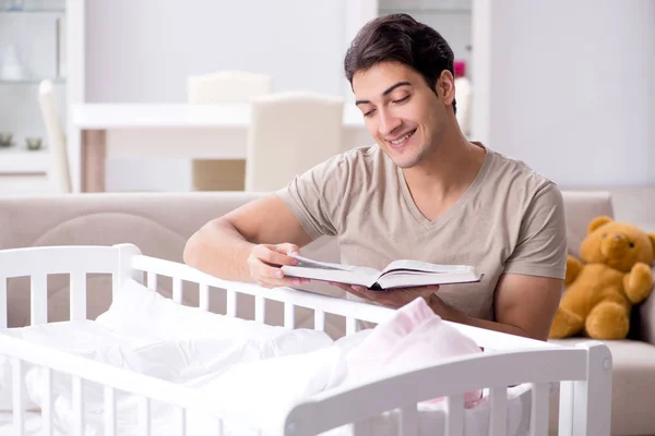 Young dad student preparing for exams and looking after baby — Stock Photo, Image