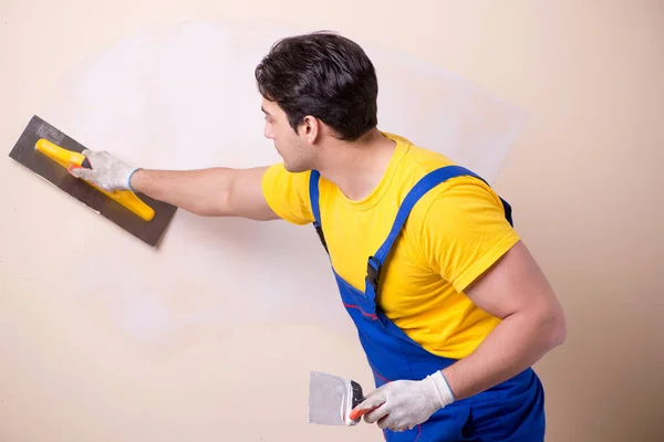 Empleado joven contratista aplicando yeso en la pared — Foto de Stock